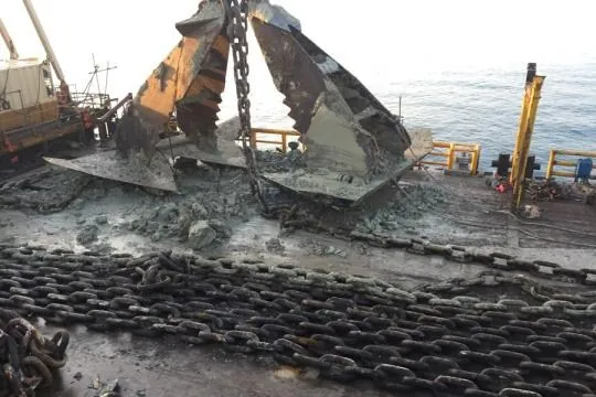 Recovered anchors and heavy chain arranged on a vessel deck